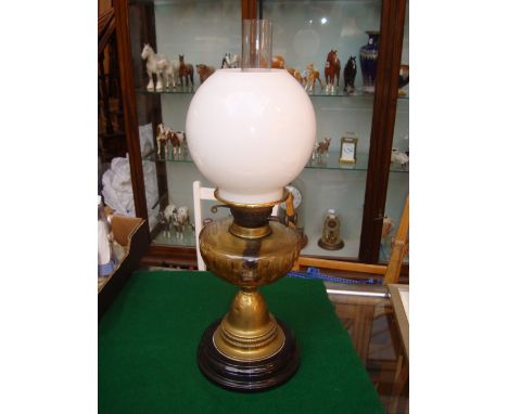 A late Victorian Veritas brass oil lamp, with clear cut glass reservoir and white glass globe shade on ceramic plinth base. 