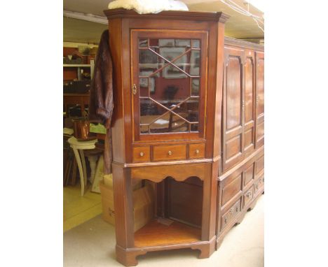 An early 19th Century and later free standing mahogany corner cupboard, the upper section with astragal glazed cupboard door 