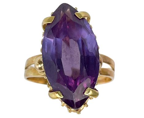 An 18ct synthetic marquise cut purple corundum stone set ring. The stone measures 19.2 x 10 x 6.1mm, within a twisted wire ba