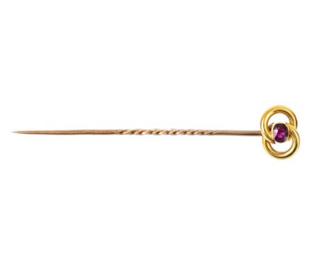 A 15ct tie pin set with a small oval cut ruby. The head with applied plaque stamped 15ct, with a gold pin, length 5.5cm, 1.2g