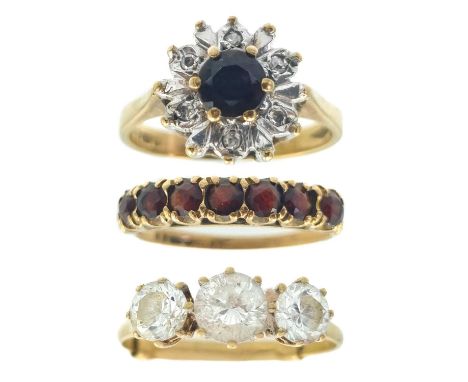 Three 9ct gem set rings. One is a garnet and small diamond cluster ring, size L, a garnet seven stone ring, size O, and a whi