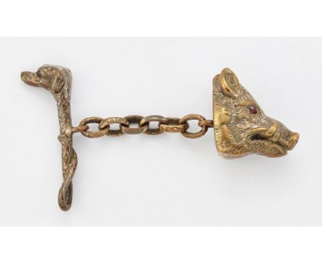 A NOVELTY HUNTING CLOAK CLASP,&nbsp;modelled as a boar's head chain-linked to a crop with dog's head terminal, with garnet in