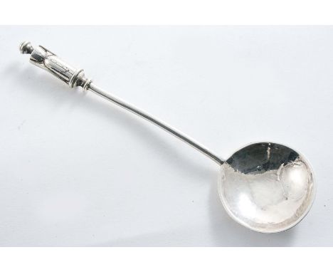 AN EDWARDIAN SPOON with a thick wire stem, a shallow circular bowl with a hammered finish and a stylised female figure finial