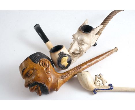 CLAY PIPES One with bowl carved as a horned devil, composition stem, 19.5 cms, a pipe with painted head by T. Holland no. 227