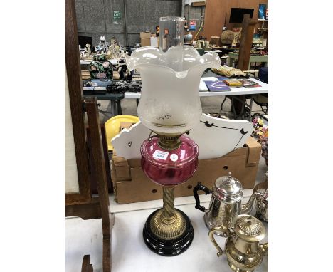 A VICTORIAN BRASS OIL LAMP WITH CRANBERRY GLASS RESERVOIR AND TWIST COLUMN SUPPORT 