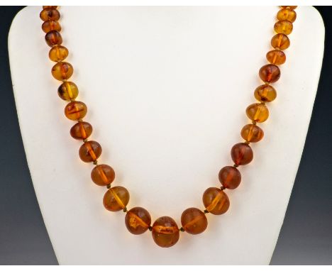 A Baltic amber necklace, early 20th century, the unevenly shaped, graduated beads with various mottled inclusions and compres