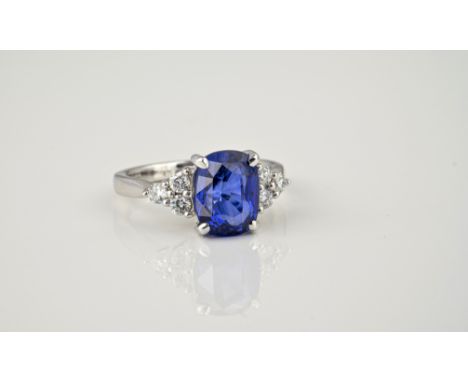 An 18ct white gold, sapphire and diamond ring, the 4.01 cushion cut sapphire of fine colour, over shoulders each set with thr