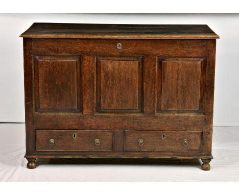 A mid 18th century oak mule chest, with hinged three plank lid over panelled front and sides and two drawers at base with bra