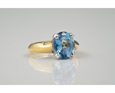 An 18ct gold, blue topaz and diamond ring, London hallmarks, the oval cut topaz over a bladed shank inset with a single brill