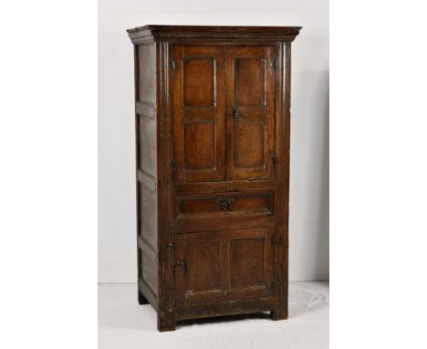 An early 18th century joined oak food cupboard, the stepped, moulded top over a pair of double panelled doors on iron hinges,