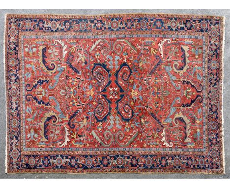 A Heriz carpet, probably early 20th century, the madder field with all over stylised floral and foliate motifs and palmettes,