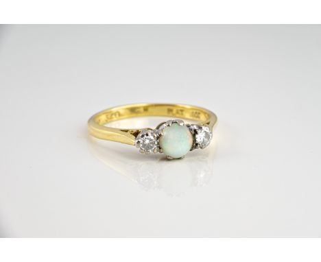 An 18ct yellow gold, platinum, opal and diamond ring, the 5.8mm. round milk opal flanked by two 0.07ct brilliant cut diamonds