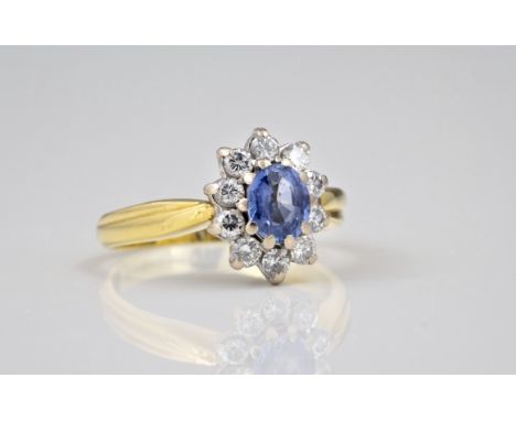 An 18ct gold, sapphire and diamond cluster ring, the cornflower blue oval cut sapphire within a floral border of ten brillian