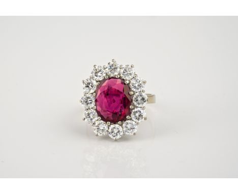 A fine 18ct white gold ruby and diamond cluster ring, the oval cut 3.91ct ruby of fine colour, within a border of twelve bril