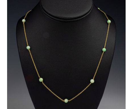 A mid-century 9ct gold and jade necklace, the fifteen 5.5mm. mottled green jade beads on a trace link chain, 30in. (76.2cm.) 