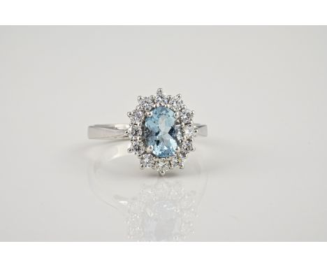 An 18ct white gold, aquamarine and diamond cluster ring, the 1.28ct oval cut aquamarine within a border of twelve brilliant c