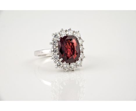 A fine 18ct white gold, Siamese ruby and diamond cluster ring, the cushion cut 5.49ct ruby within a border of fourteen brilli