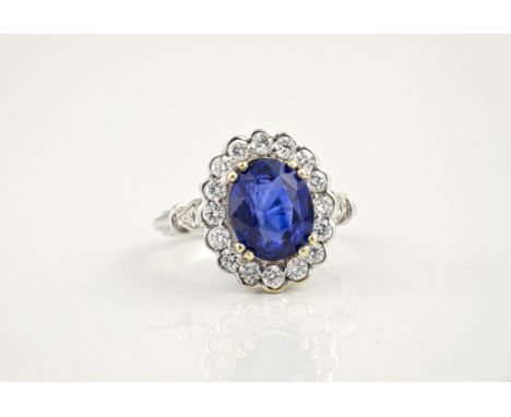 An 18ct white gold, sapphire and diamond cluster ring, the 4.43ct oval cut sapphire within a scalloped border of sixteen bril