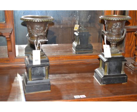 A pair of 19th Century brass and slate garnitures, each of urn campana form decorated with putti, on architectural base, 36cm