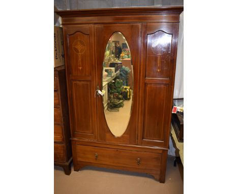 An Edwardian inlaid mahogany wardrobe, bevelled mirror door above a single drawer, 128cms wide.