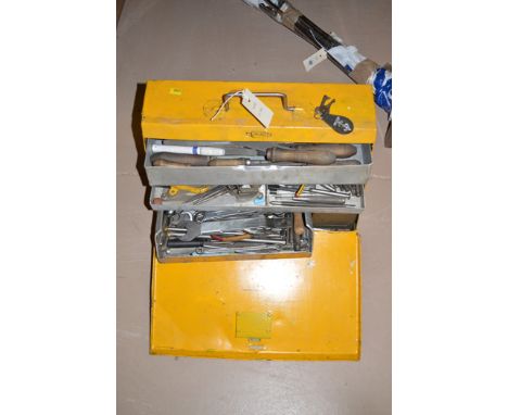 A collection of tools, files, spanners, hammers, drills and other items in a yellow metal painted toolbox.