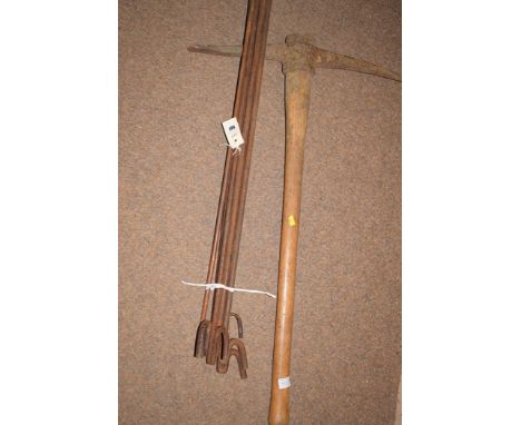 A pick axe together with a bundle of metal garden poles.