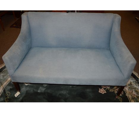 An Edwardian two-seater settee, raised on square mahogany tapering legs terminating in ceramic castors, upholstered in blue m