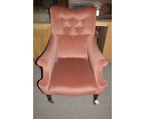 A Victorian armchair upholstered in pink velour material, raised on turned mahogany legs terminating in ceramic castors.