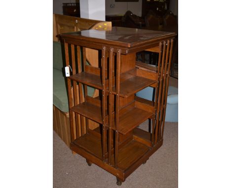 An early 20th Century oak revolving bookcase, by Maple & Co., quatreform base terminating in ceramic castors (damages).