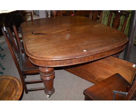 A Victorian mahogany extending dining table (three spare leaves), raised on turned and reeded legs terminating in ceramic cas