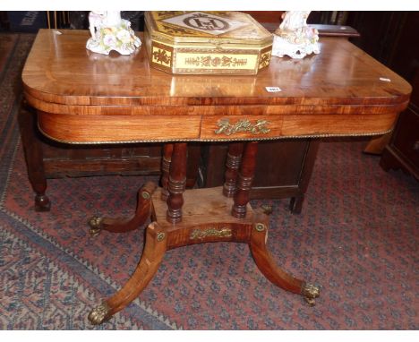 19th century fold over card table on four turned columns above platform base, with downswept legs and brass claw feet