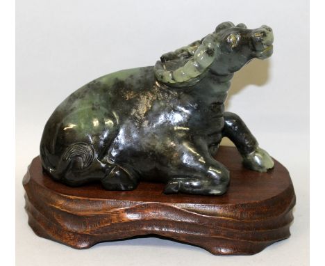 A 20TH CENTURY CHINESE JADE MODEL OF A WATER BUFFALO, together with a fitted wood stand, the stone of predominantly dark gree