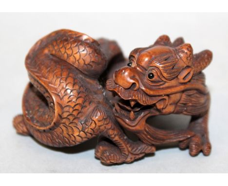 A GOOD QUALITY 19TH/20TH CENTURY SIGNED JAPANESE CARVED WOOD OKIMONO OF A COILED DRAGON, with inlaid eyes, its scales engrave