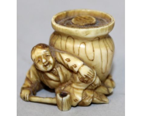 AN EARLY 20TH CENTURY JAPANESE IVORY NETSUKE, carved in the form of a man holding a mallet and reclining next to a storage ja