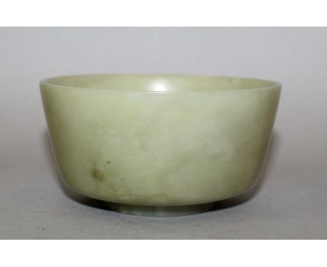 A CHINESE CELADON JADE-LIKE BOWL, with flaring sides, the stone with darker and paler inclusions, 4.3in diameter & 2.2in high