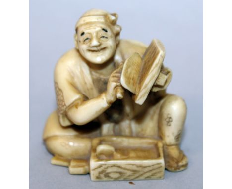 AN EARLY 20TH CENTURY SIGNED JAPANESE IVORY NETSUKE OF A SEATED ARTISAN, with tools and wood grained box, the base with an en