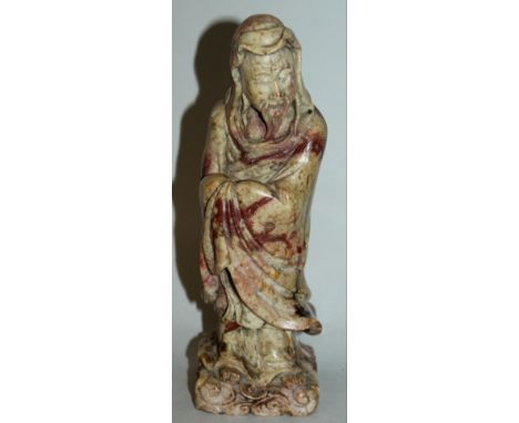 A GOOD QUALITY 19TH CENTURY CHINESE CARVED SOAPSTONE FIGURE OF AN IMMORTAL, standing on a cloud scroll base, his robes pulled