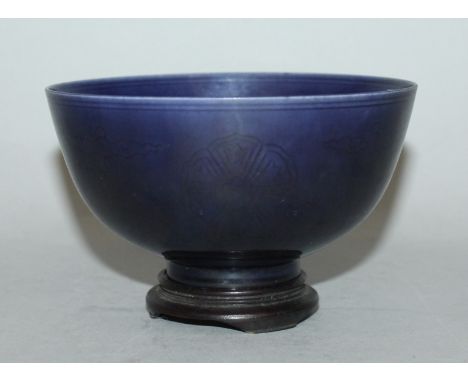 A CHINESE BLUE GLAZED PORCELAIN BOWL, together with a fitted wood stand, the rounded exterior sides faintly incised beneath t