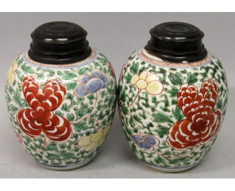 A PAIR OF LATE 17TH CENTURY CHINESE KANGXI PERIOD WUCAI PORCELAIN JARS, with fitted hardwood covers, each painted with scroll