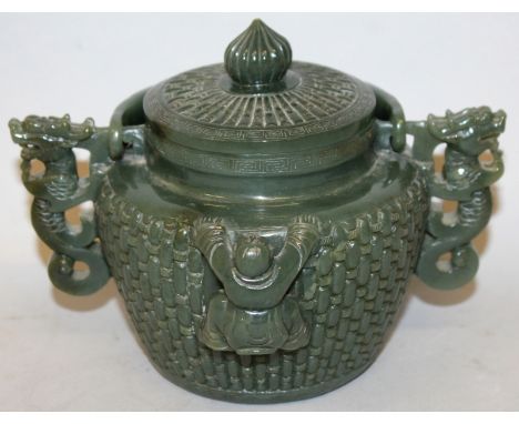 A CHINESE SPINACH JADE-LIKE JAR & COVER, with overhead swing handle, the sides decorated in high relief with two boys clamber