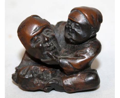A 19TH/20TH CENTURY JAPANESE CARVED WOOD NETSUKE OF A MASK MAKER, seated and holding a mask of Fukurokuju, 1.3in wide & 1.25i