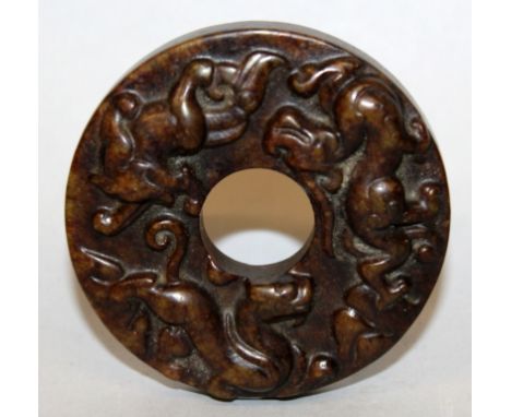 A CHINESE BROWN JADE-LIKE BI DISC, of archaic design, one surface decorated in relief with chilong, the reverse surface with 