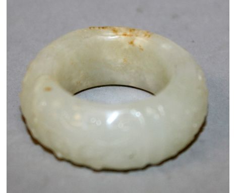 A CHINESE WHITE JADE RING, the outer surface with archaic taotie mask relief decoration, the stone with opaque white and russ