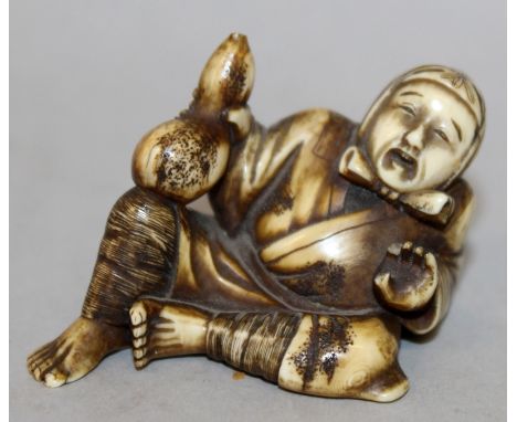 AN EARLY 20TH CENTURY JAPANESE STAINED IVORY NETSUKE OF A RECLINING MAN, holding a gourd in one hand, 1.9in wide & 1.4in high