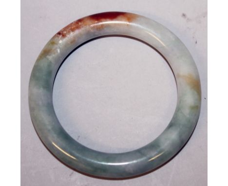 A GOOD QUALITY 19TH/20TH CENTURY CELADON JADE BANGLE, the predominantly green stone with some russet inclusions, 3.25in diame