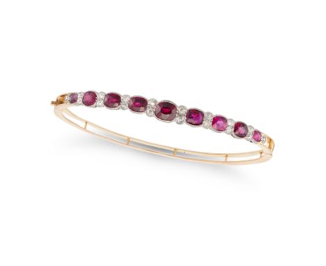 A RUBY AND DIAMOND BANGLE the hinged bangle set with a row of cushion cut rubies accented by old cut diamonds, the rubies all