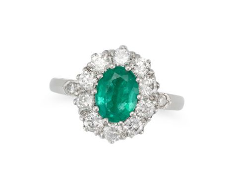 AN EMERALD AND DIAMOND CLUSTER RING in platinum, set with an oval cut emerald of approximately 1.10 carats in a cluster of ro