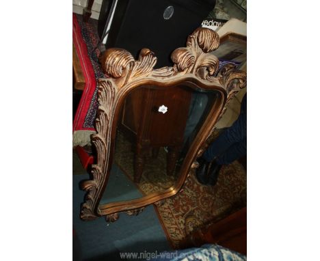 An unusual shaped, bevelled wall Mirror, the frame representing scrolling foliage and surmounted by a triple scroll detail re