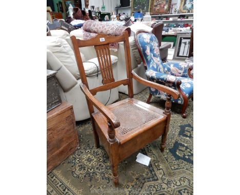 A satinwood framed open armed Commode Armchair having a caned seat, a fretworked central splat and turned front legs.
