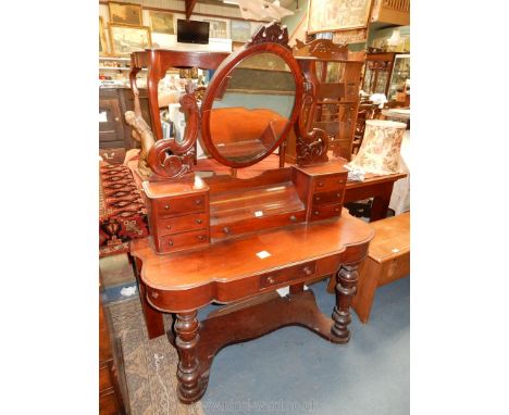 A Duchess type Mahogany Dressing Table, the oval mirror raised on supports with seven small drawers, the top with a frieze dr